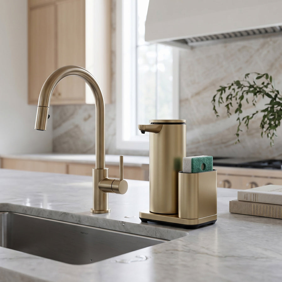 Simplehuman's 14 oz. Liquid Sensor Pump with Caddy in Matte Gold in a modern kitchen setting with marble countertops and backsplash featuring wooden cabinets.